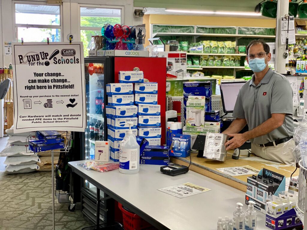 A cashier poses with a Round Up for the Schools poster at Carr Hardware checkout counter