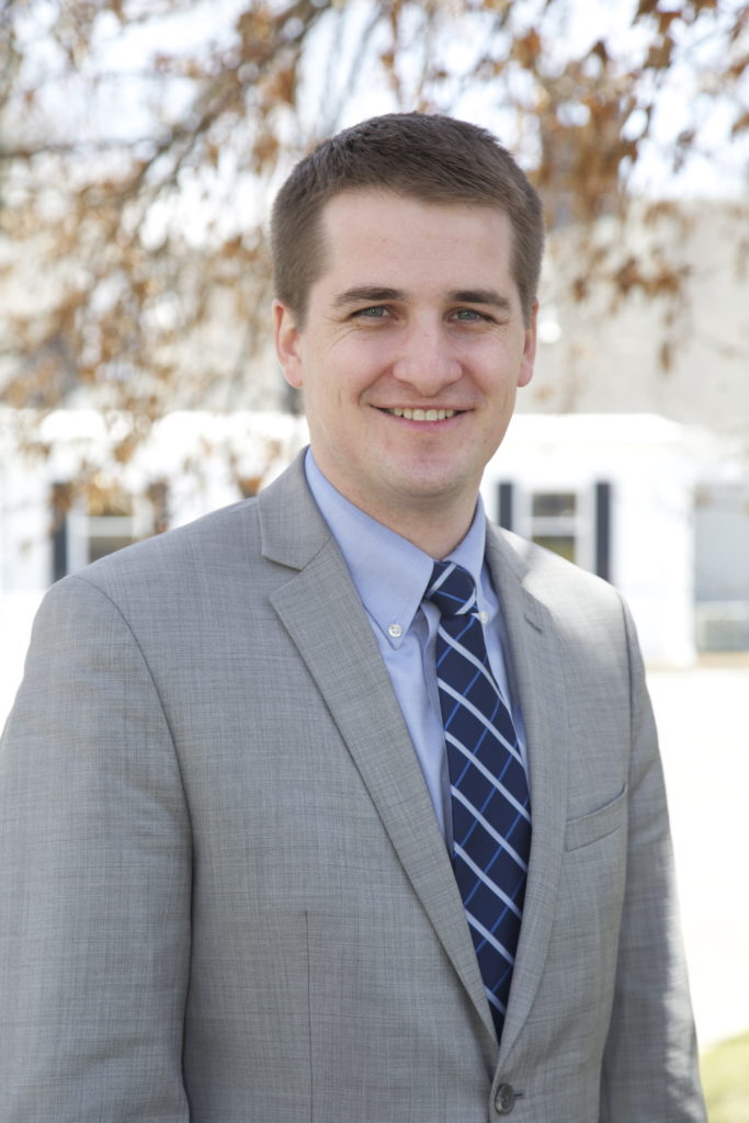 Man in suit standing outside in front of a white building